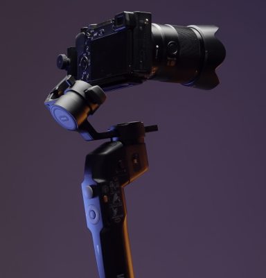 The concept of shooting with gadgets. Action.A large swivel tripod on which a large video camera is attached shoots in different directions on a bright purple background. High quality 4k footage