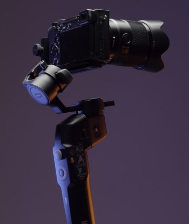 The concept of shooting with gadgets. Action.A large swivel tripod on which a large video camera is attached shoots in different directions on a bright purple background. High quality 4k footage